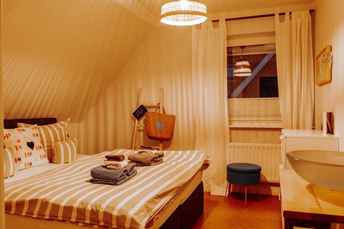 Helles Schlafzimmer mit einem Bett, Tisch, Waschbecken und Fenstern.